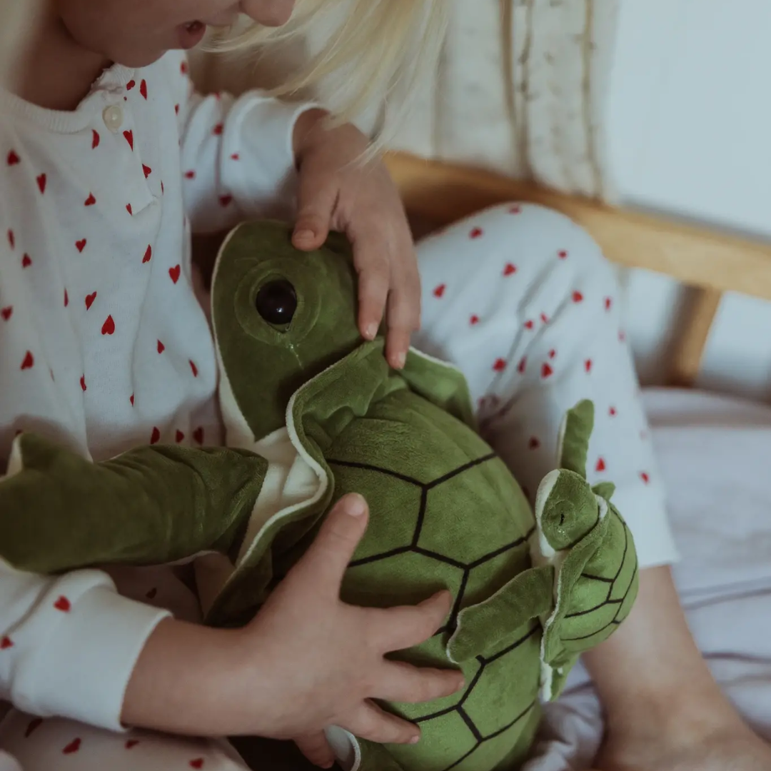 Groene ByASTRUP verzwaringsknuffel schildpad van 1,6 kg met klein schildpadje op haar schild wordt lekker geknuffeld door een meisje